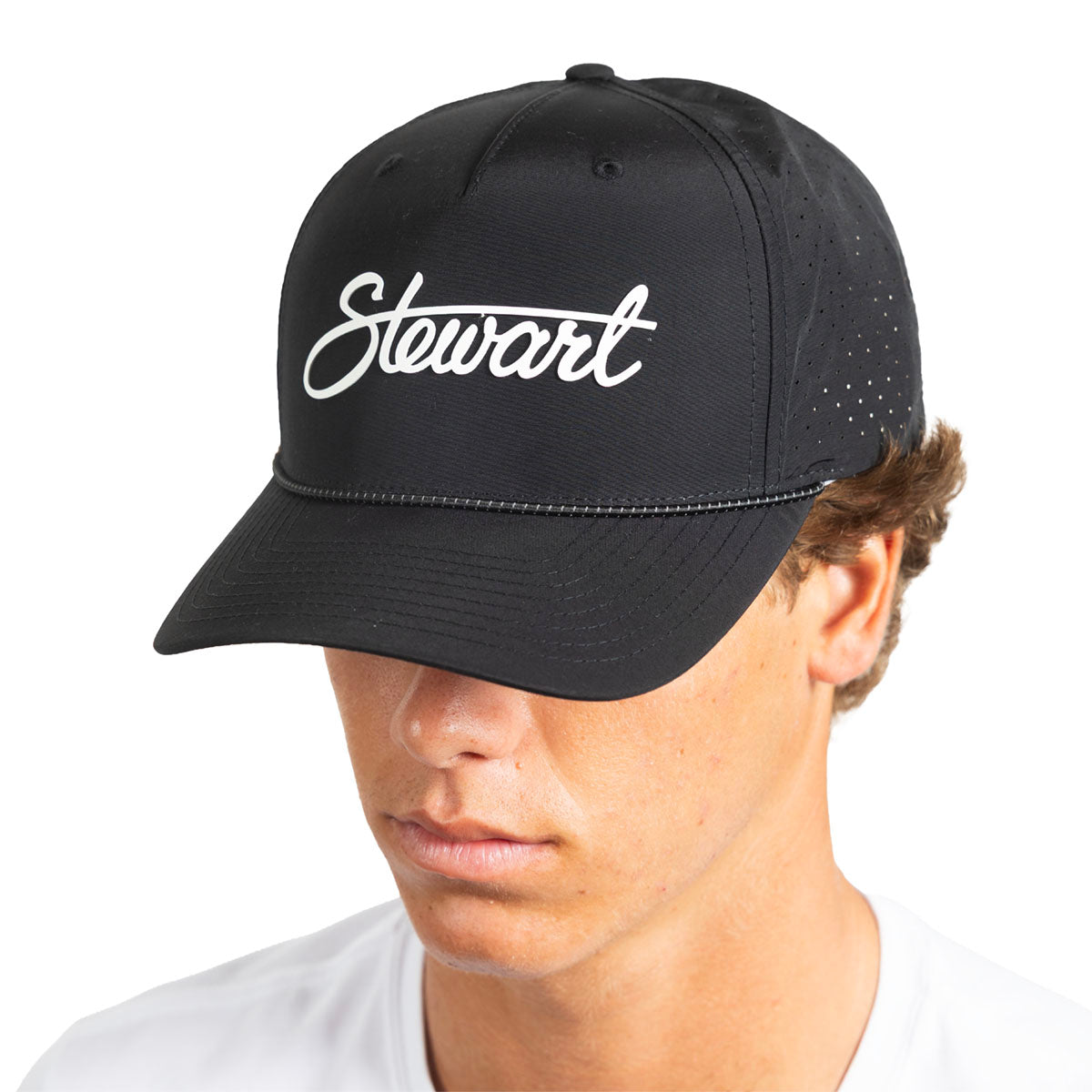 A man wearing a black baseball cap with 'Stewart' embroidered in white script on the front, shown against a plain white background.