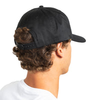 A man shown from the back wearing a black baseball cap with an adjustable strap, photographed against a plain white background.