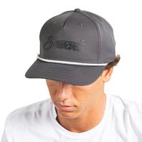A man wearing a dark gray baseball cap with a white rope detail and the brand name 'Stewart' embroidered on the front, against a plain white background.
