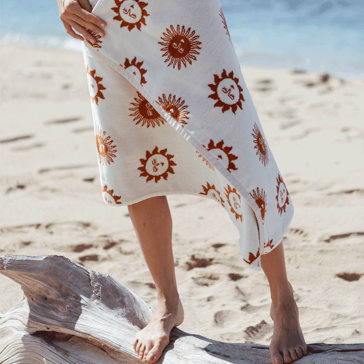 Person holding a towel with sun patterns on a sandy beach