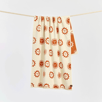 Towel with sun and moon pattern hanging on a line against a light gray background