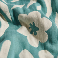 Close-up of a teal and white floral patterned fabric with a green flower emblem.