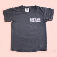Black t-shirt with 'Let's Go Surfing' text on a pink background