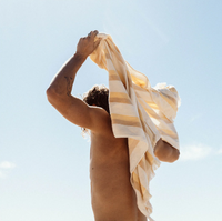 Person with a striped towel draped over their shoulder against a clear blue sky