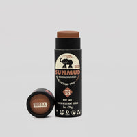 SunMud mineral sunscreen stick with black packaging and brown applicator on a light gray background