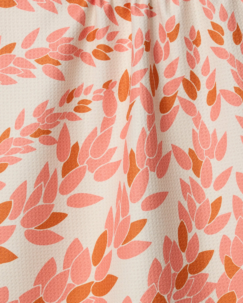 Fabric with a pattern of pink and orange leaves on a white background