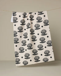 White towel with black shell pattern hanging on a line against a beige background