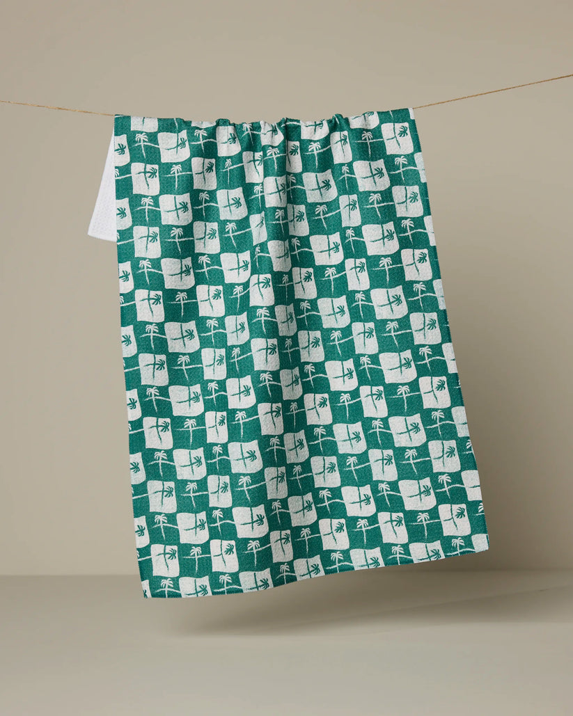Green and white patterned towel hanging on a line against a beige background