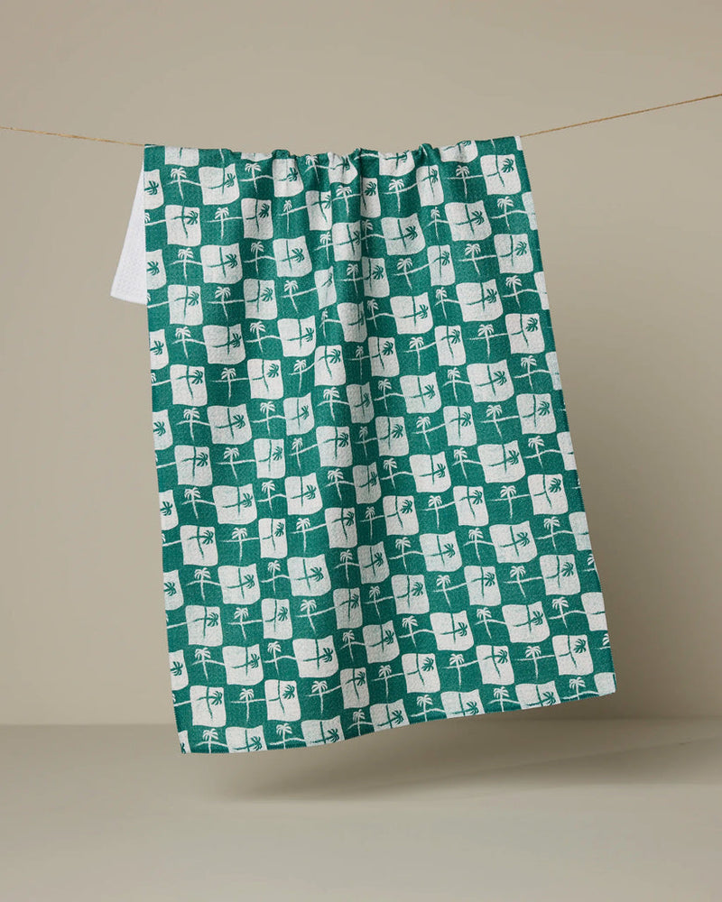 Green and white patterned towel hanging on a line against a beige background