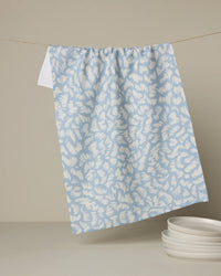 Blue and white patterned towel hanging on a line with plates below.