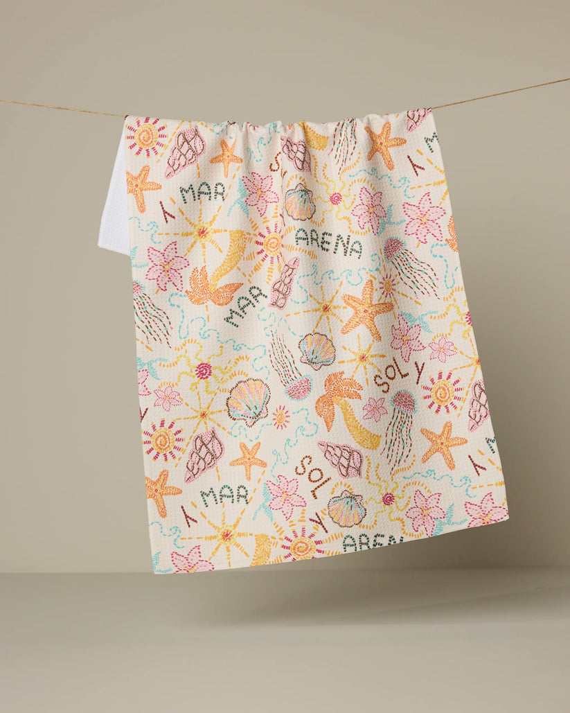 Colorful towel with beach-themed patterns hanging on a line against a beige background