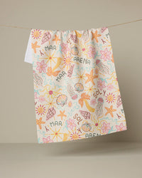 Colorful towel with beach-themed patterns hanging on a line against a beige background