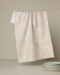 Towel with shell pattern hanging on a line, with plates in the background