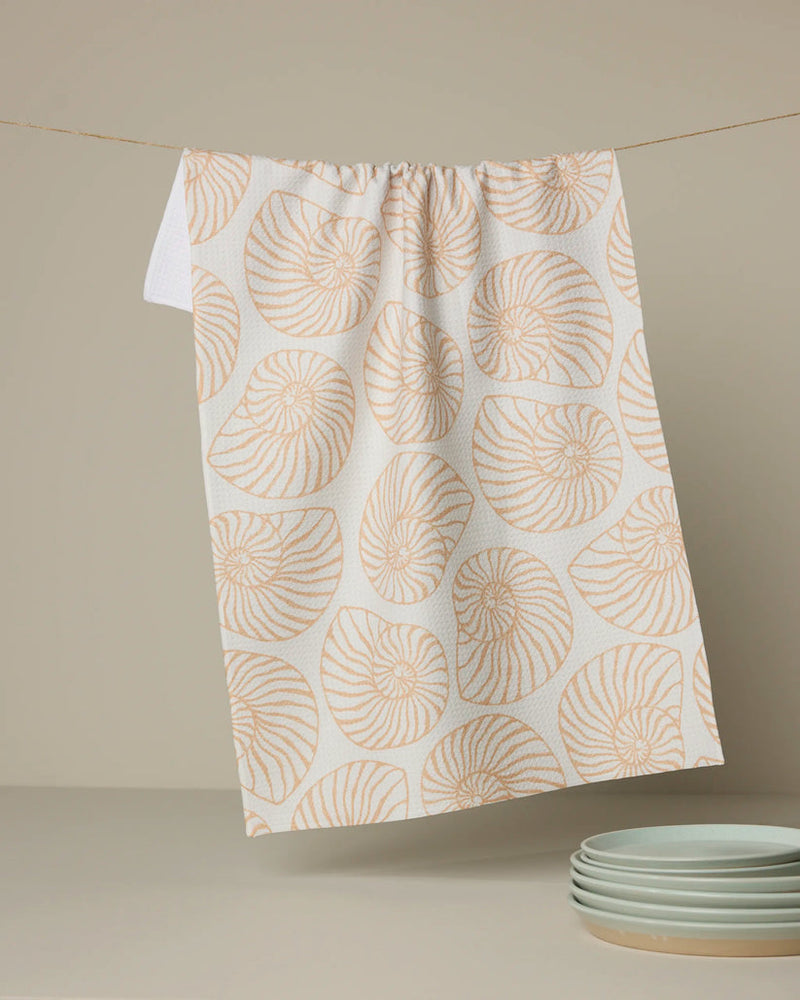 Towel with shell pattern hanging on a line, with plates in the background