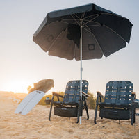 Beach umbrella and chairs on a sandy beach with a sunset in the background