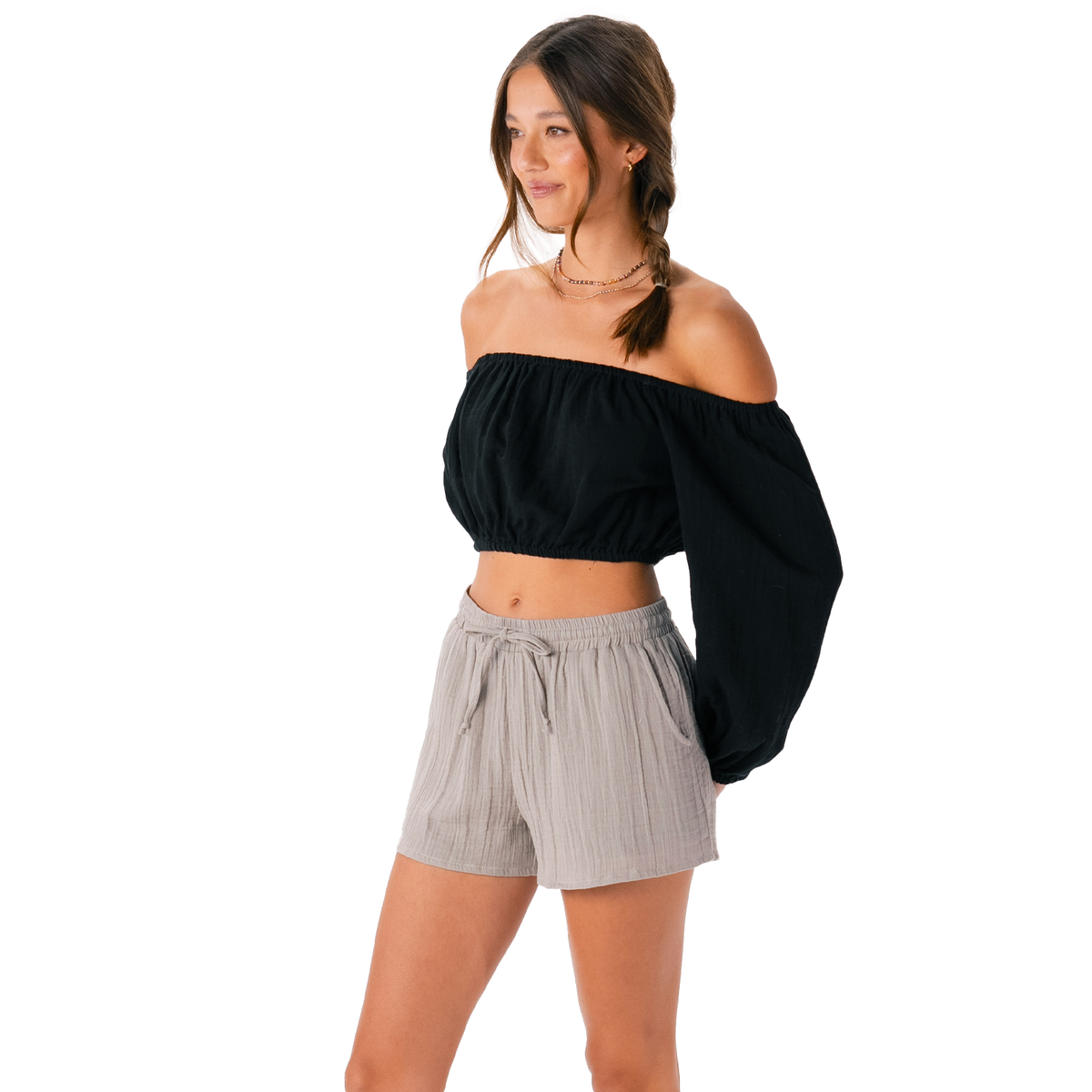 Woman wearing a black off-shoulder top and gray shorts on a white background