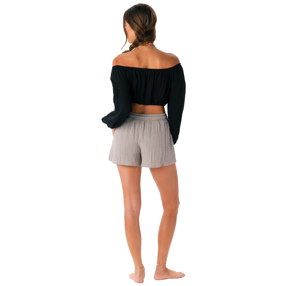 Woman wearing a black off-shoulder top and gray shorts on a white background