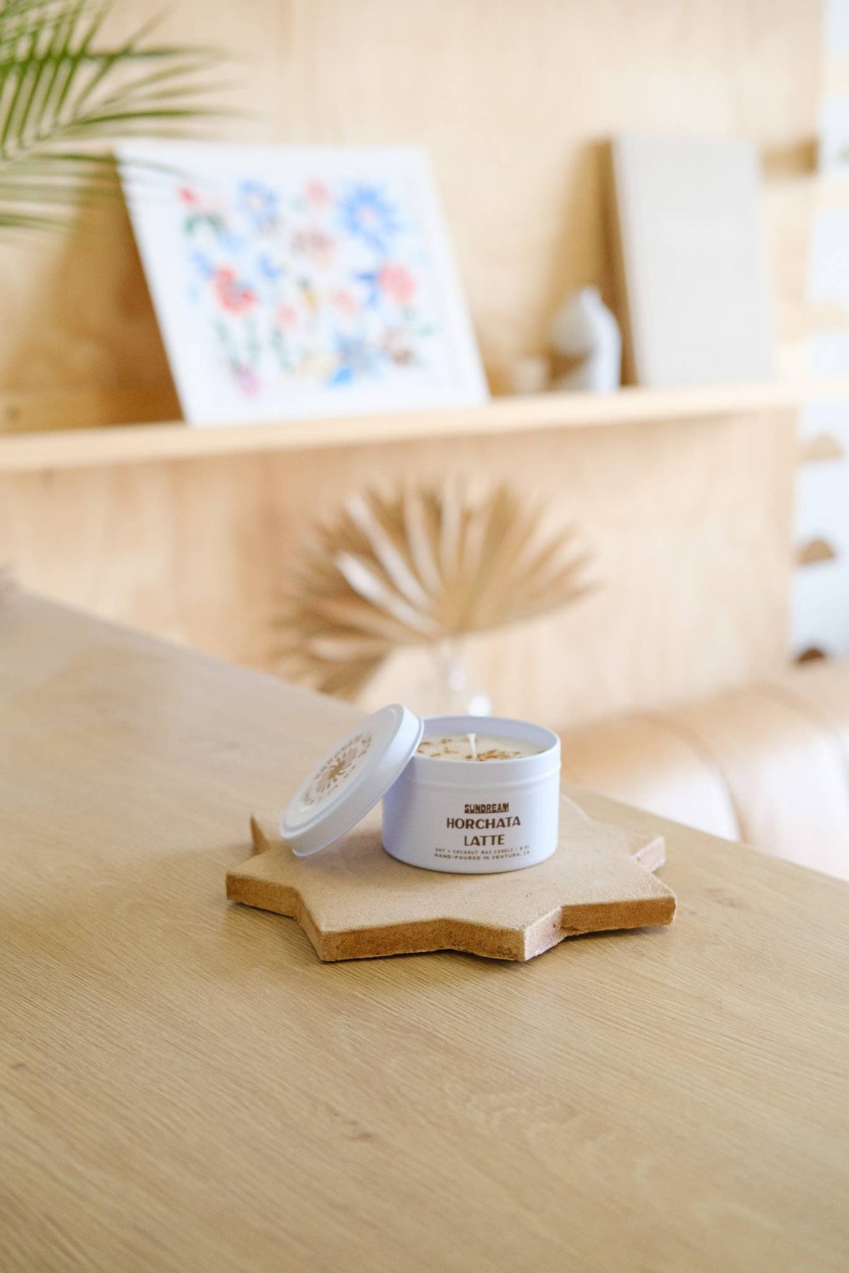 Small container of cream on a wooden coaster with a blurred indoor setting in the background