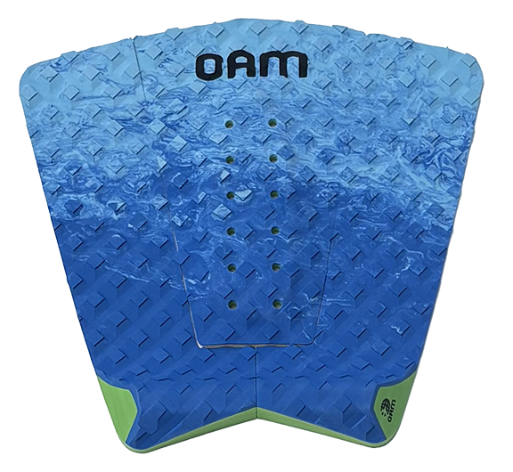 A blue diamond-plate textured surfboard tail pad with green accents at the bottom corners and a black 'OAM' logo printed at the top, shown on a plain white background.