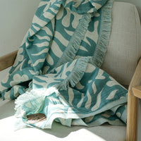 Teal and white patterned towel draped over a beige armchair.