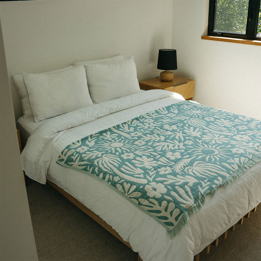 a green patterned throw towel in a room with a window.