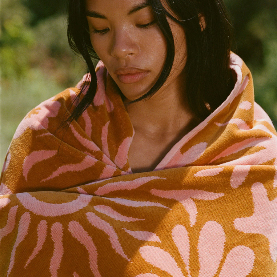 Woman wrapped in a pink and orange patterned towel outdoors