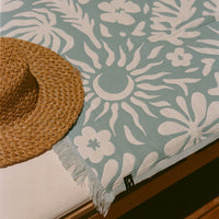 Straw hat on a floral-patterned towel with a sun design.