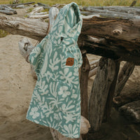 Green and white patterned towel with a brown patch on a wooden log