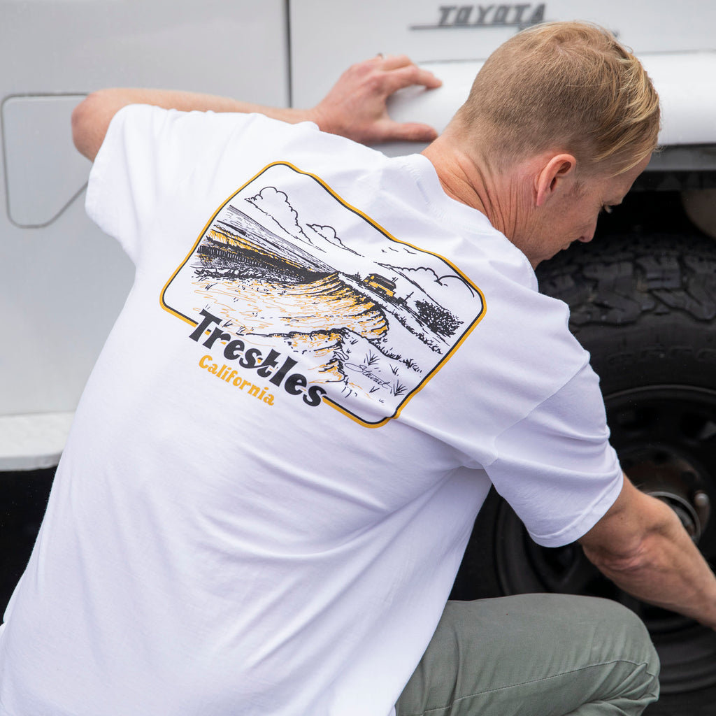 Surfer wearing the Stewart Trestles t-shirt in white, back view of shirt