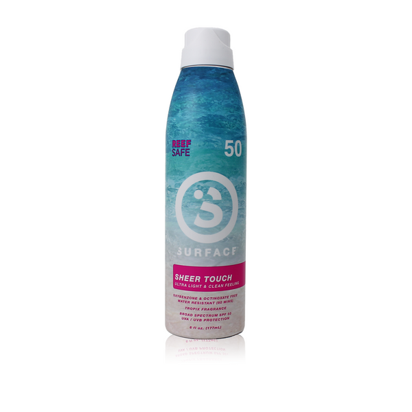 A bottle of Surface Sheer Touch SPF50 sunscreen spray with blue and white label design, indicating it's reef safe and has a tropical fragrance.