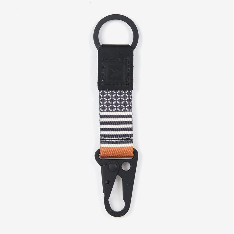 A black with stripes keychain clip with a metal key hook and ring, attached to a striped polyester strap, designed to clip to a belt loop or bag.